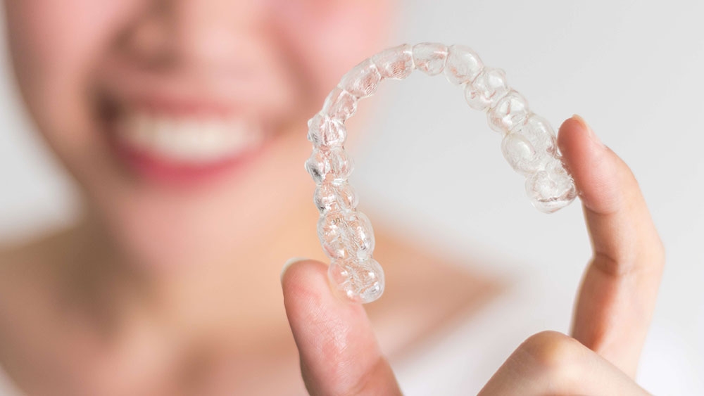 girl holding up invisalign